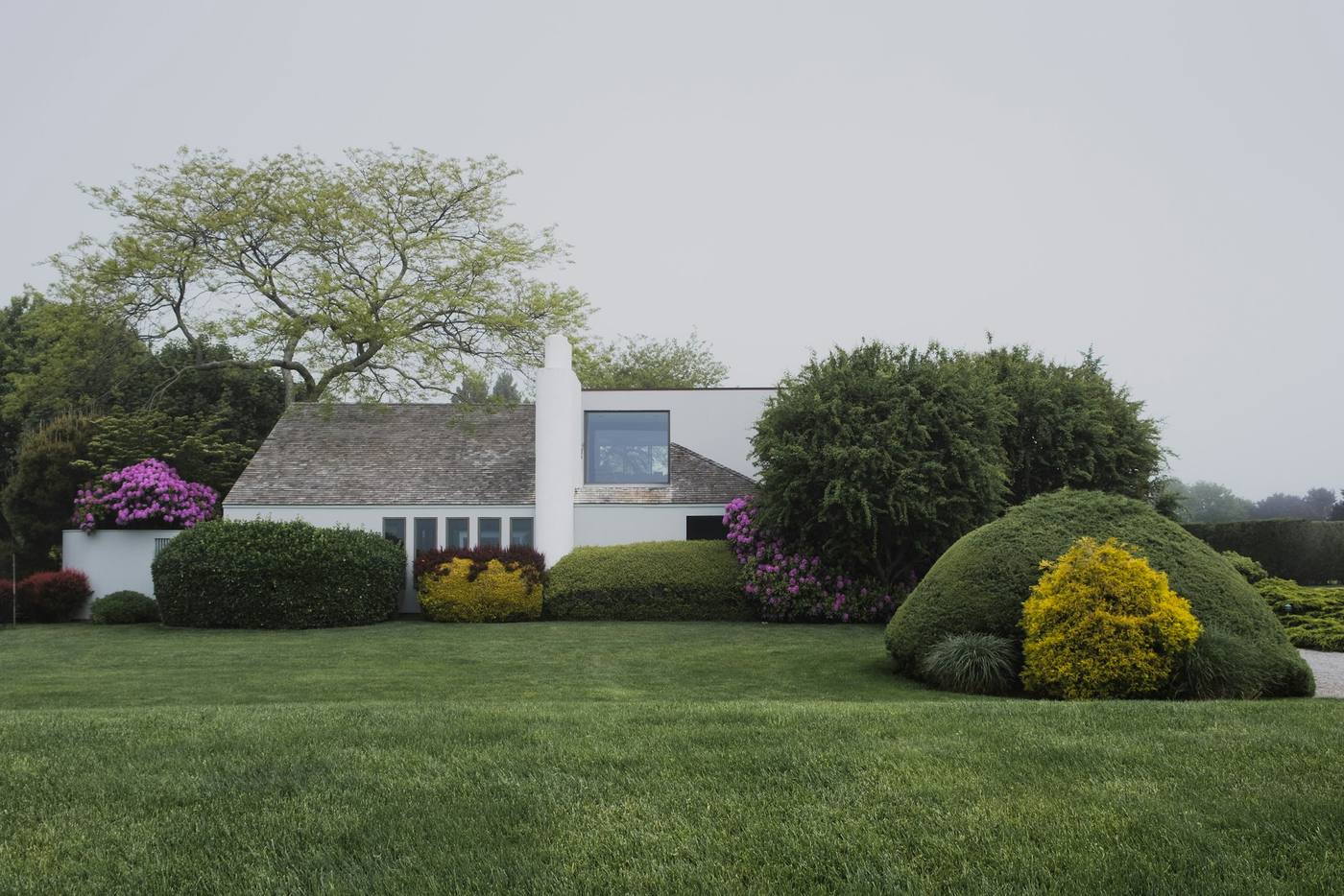 A green lawn framed by mature trees and a welcoming residential property
